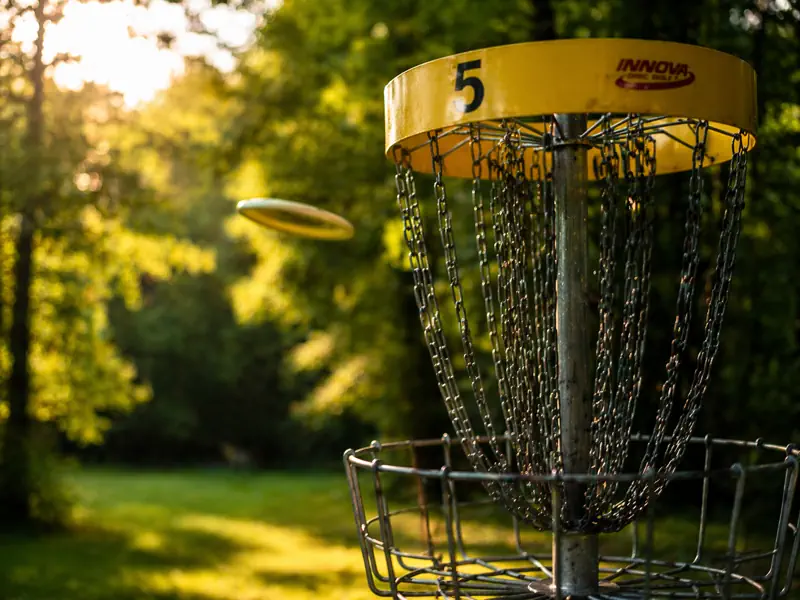 A disc golf basket with metal chains catching an incoming disc