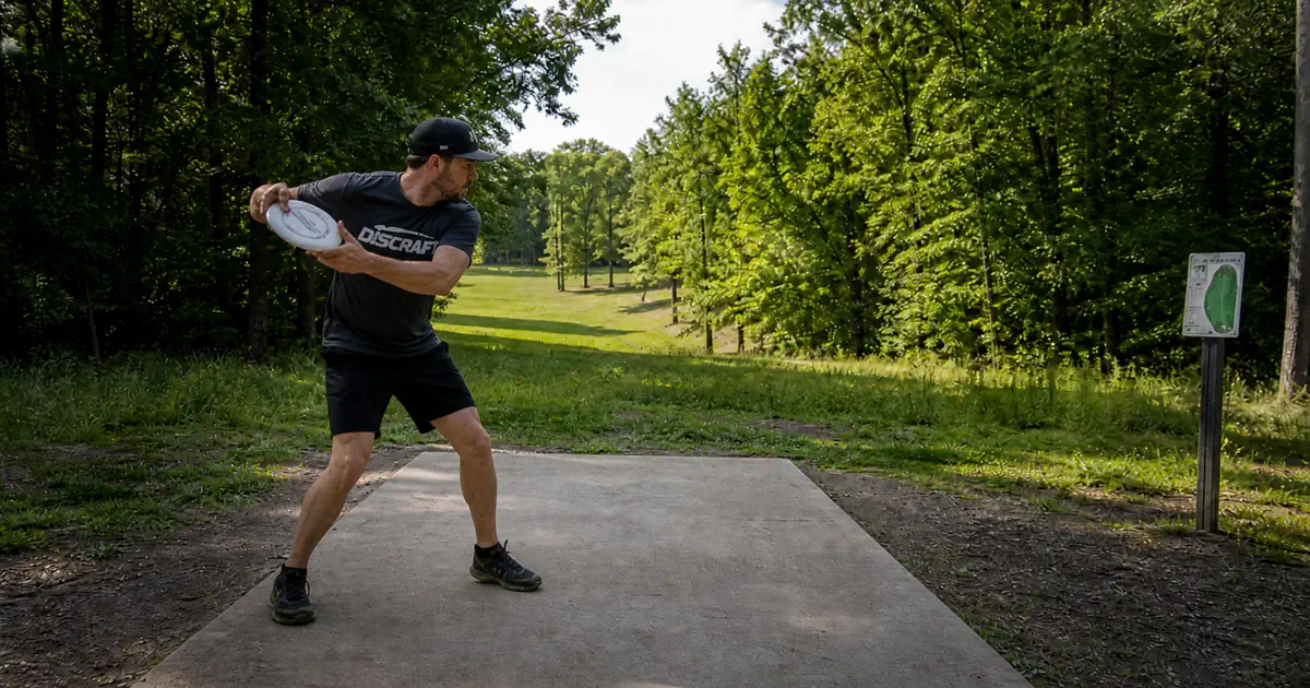 Disc golf reach back position with disc at chest height and hips coiled away from target